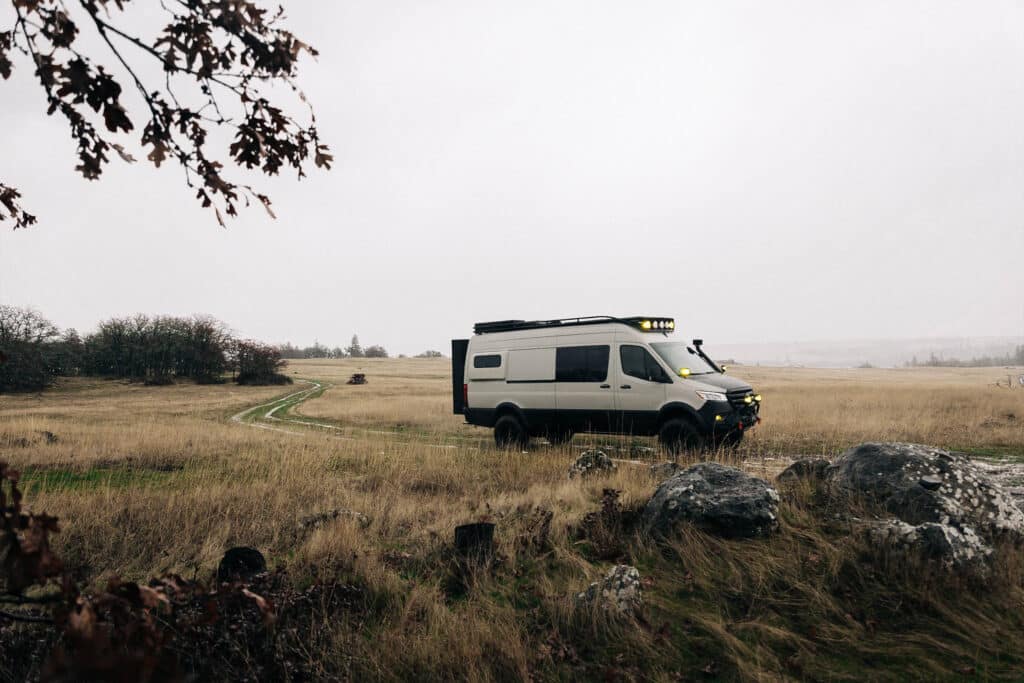 A farway view of a bechmark van parked in the middle of field