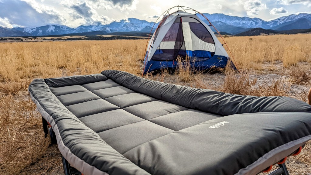 A view of a REI Co Op Kingdom Cot at a camopsite field by a camping tent