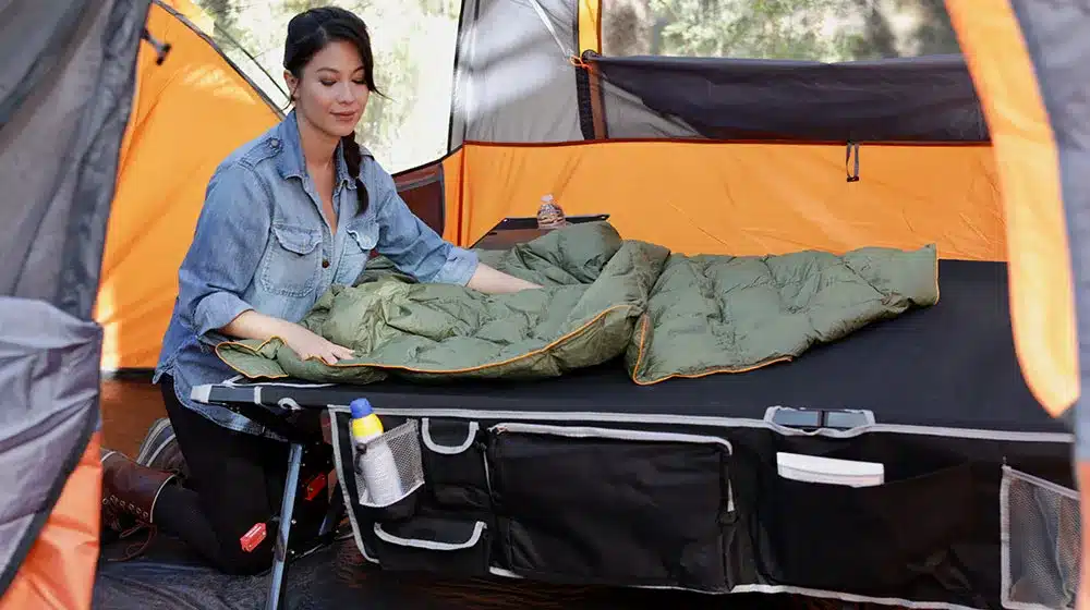 A view of a girl setting up a cot inside a camping tent