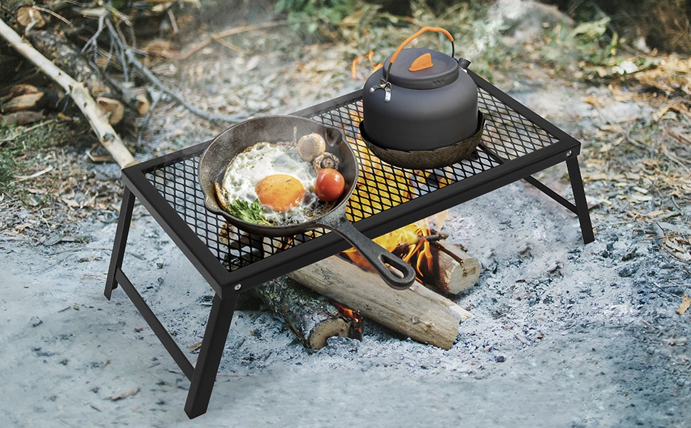 A view of a kettle and a pan with egg frying at grates of a camping grill