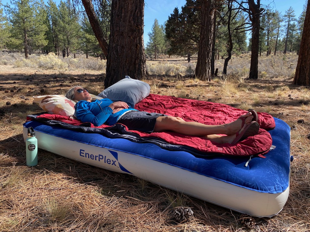 A view of a woman lying on an air mattress outdoors