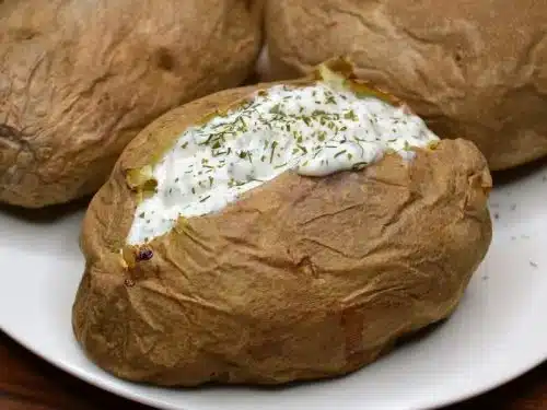 A view of baked potaotes with skin filled with cream and herbs