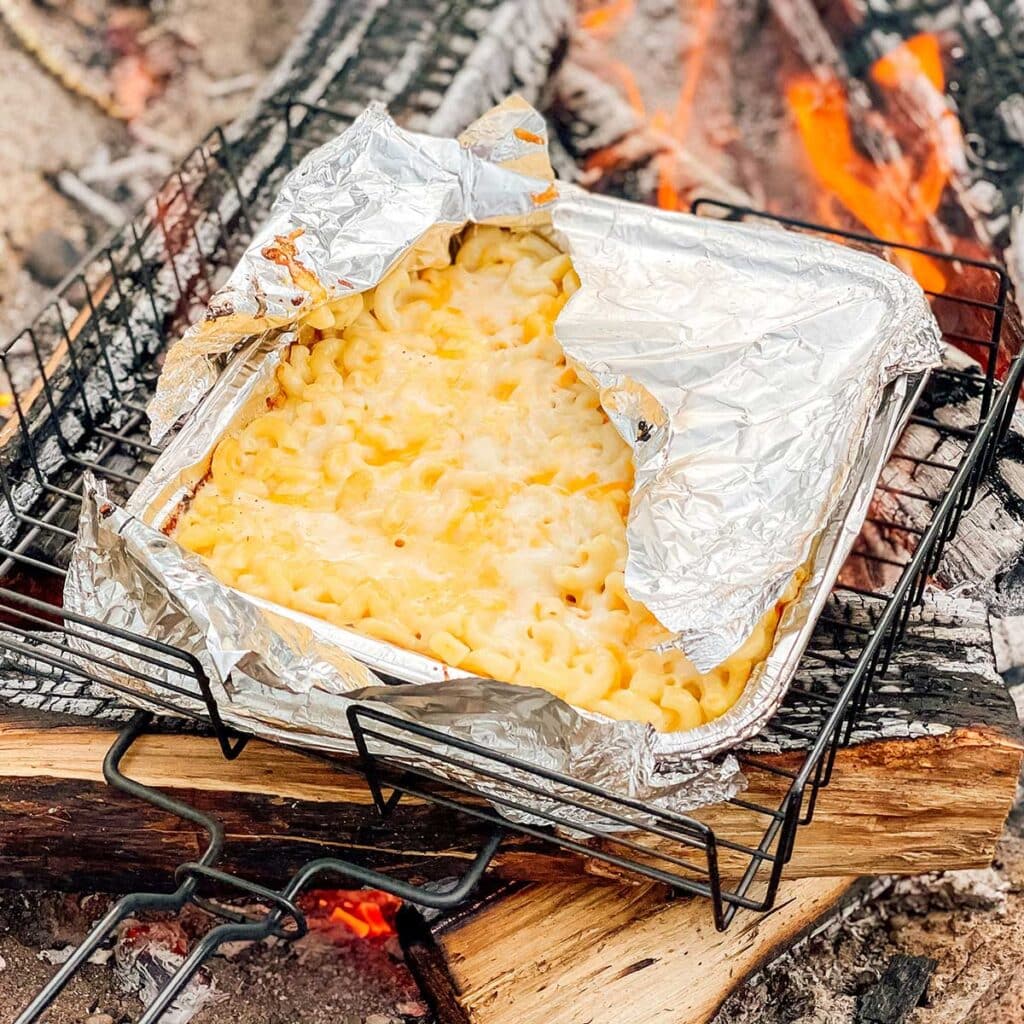 A view of mac and cheese cooked over a campfire with foil on top