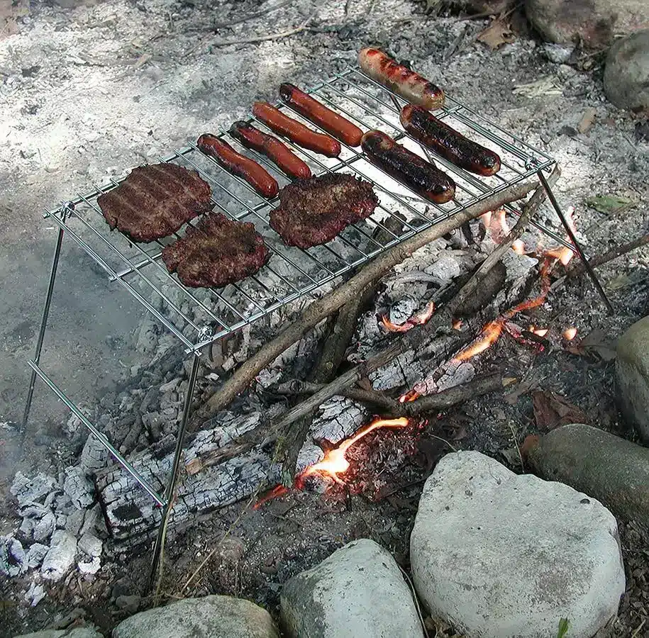 A view of steaks and sausages being cooked at the Rome Pioneer Camp Grill over rocks