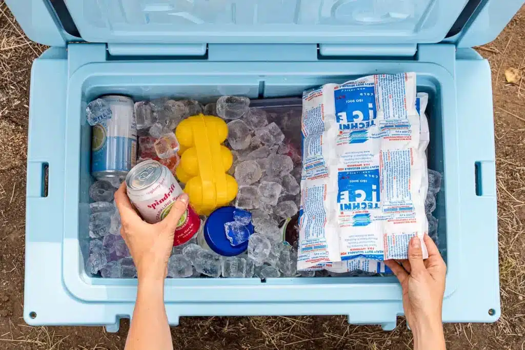 An overhead view of a cooler with ice pack soda can and ice inside