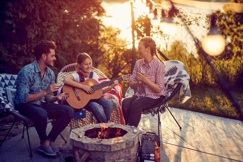 Little girl playing guitar by the fireplace, mom and dad clapping and singing along.