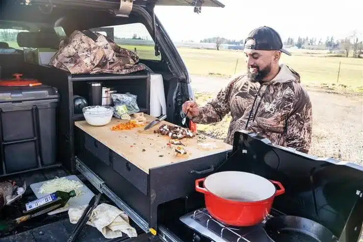 a boy cooking in a truck bed camping setup