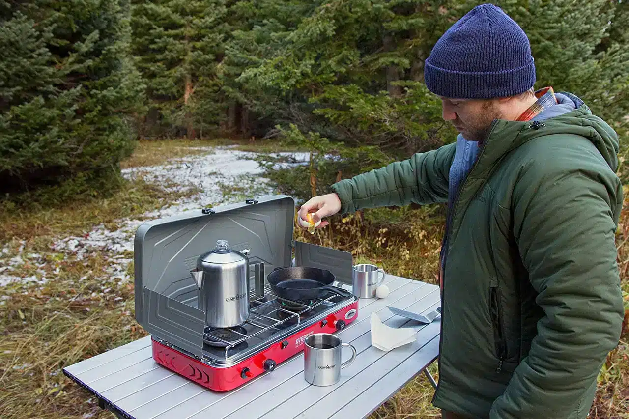 a person cooking on chef everest camping stove