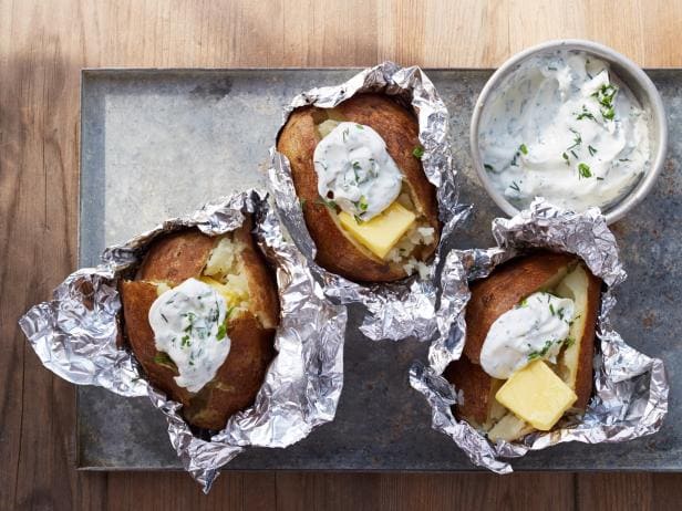 baked potatoes in aluminium foil sour cream on top