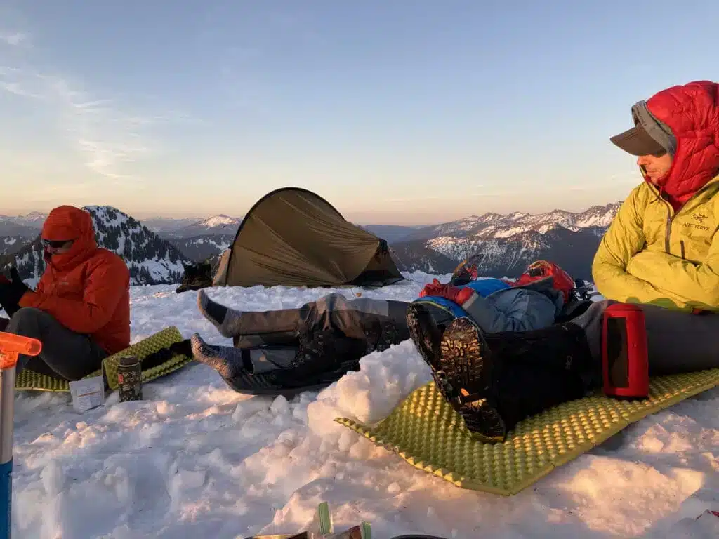 persons fully packed up in warm clothes sitting on snow