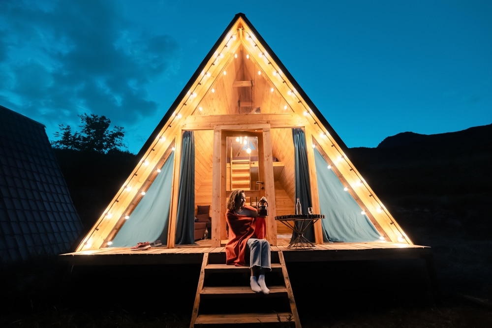 Woman Drinking Tea On The Porch Of A Wooden Lodge