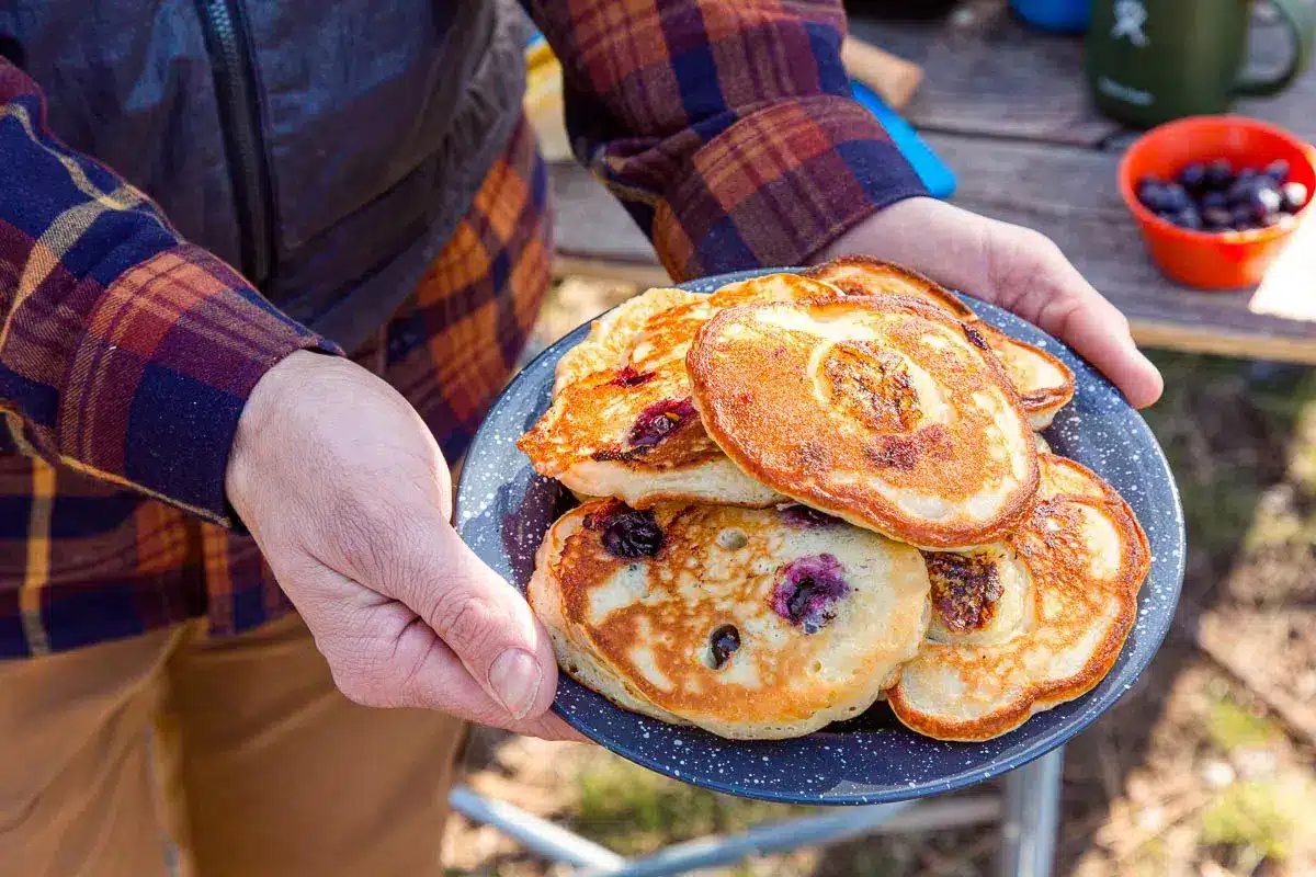 closeup of male hands holding a plate of pancakes