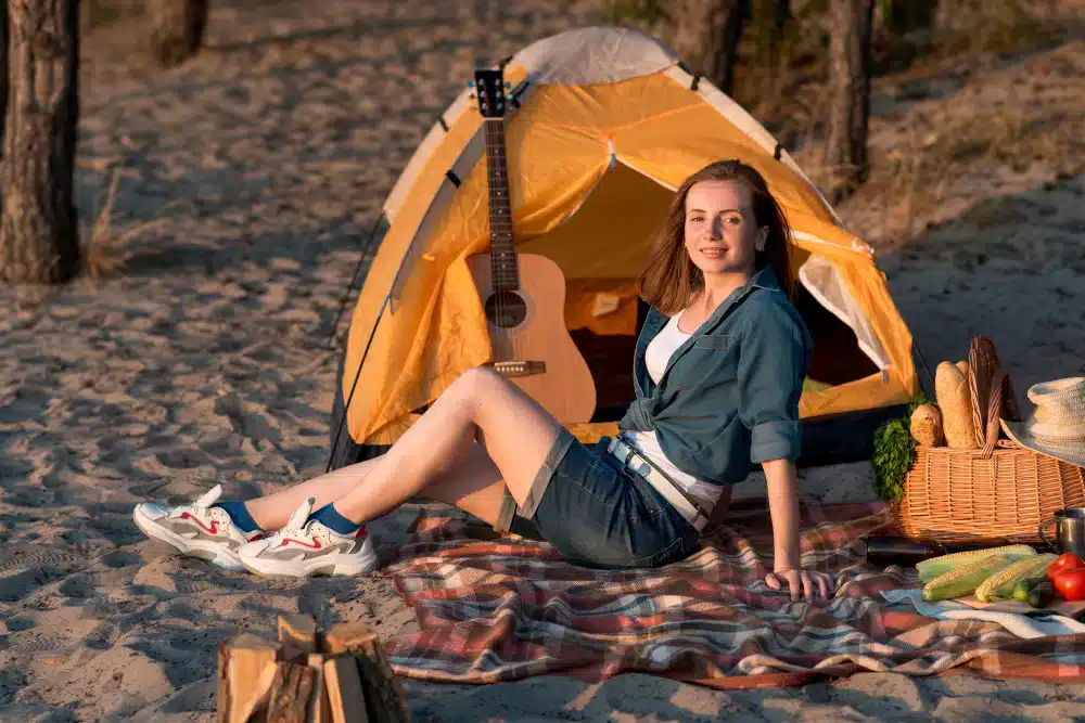 woman sitting on a blanket near a tent