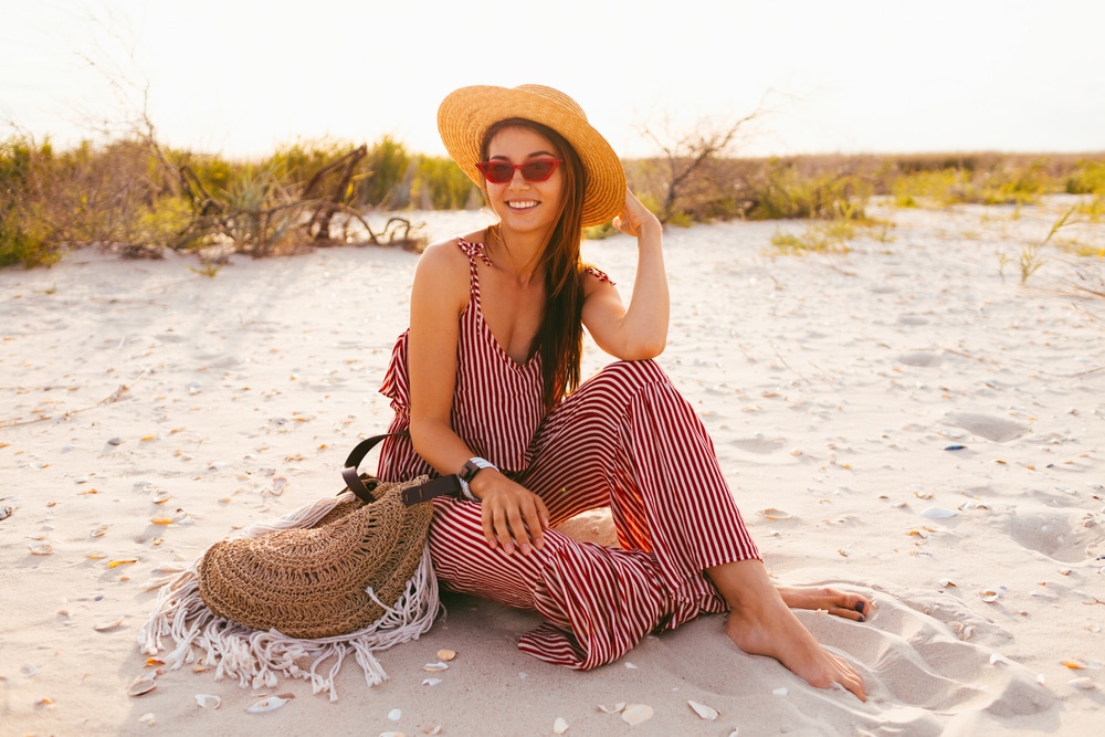 young woman in trendy summer linen straw romper and straw hat