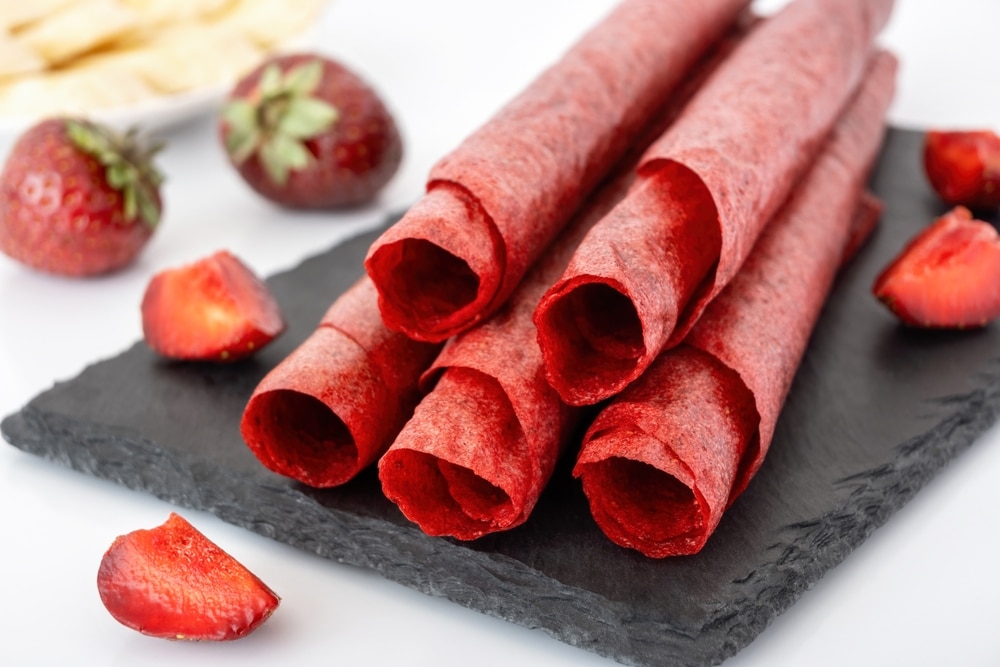 Homemade strawberry fruit leather on black slate closeup. 