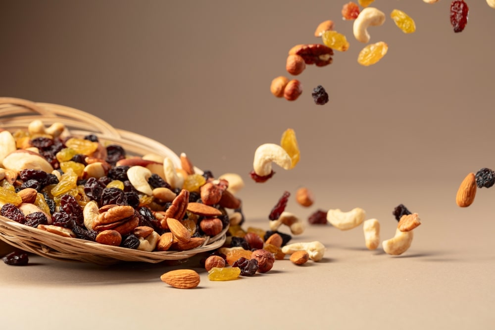 The mix of dried nuts and raisins on a beige background.